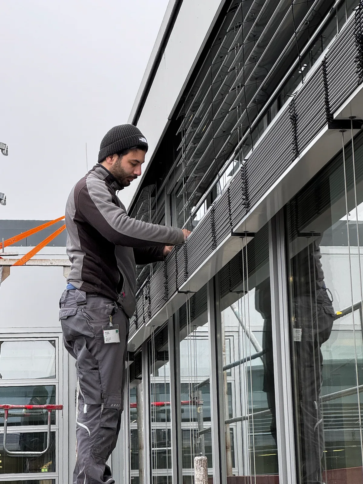 Techniker arbeitet an den Lamellen eines Raffstores an einer Glasfassade